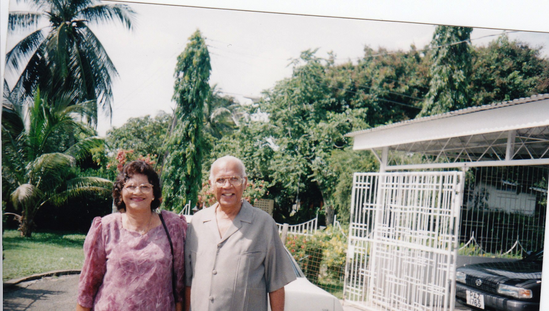 Pearl and Hafeez stand smiling in their front yard in Valsayn North