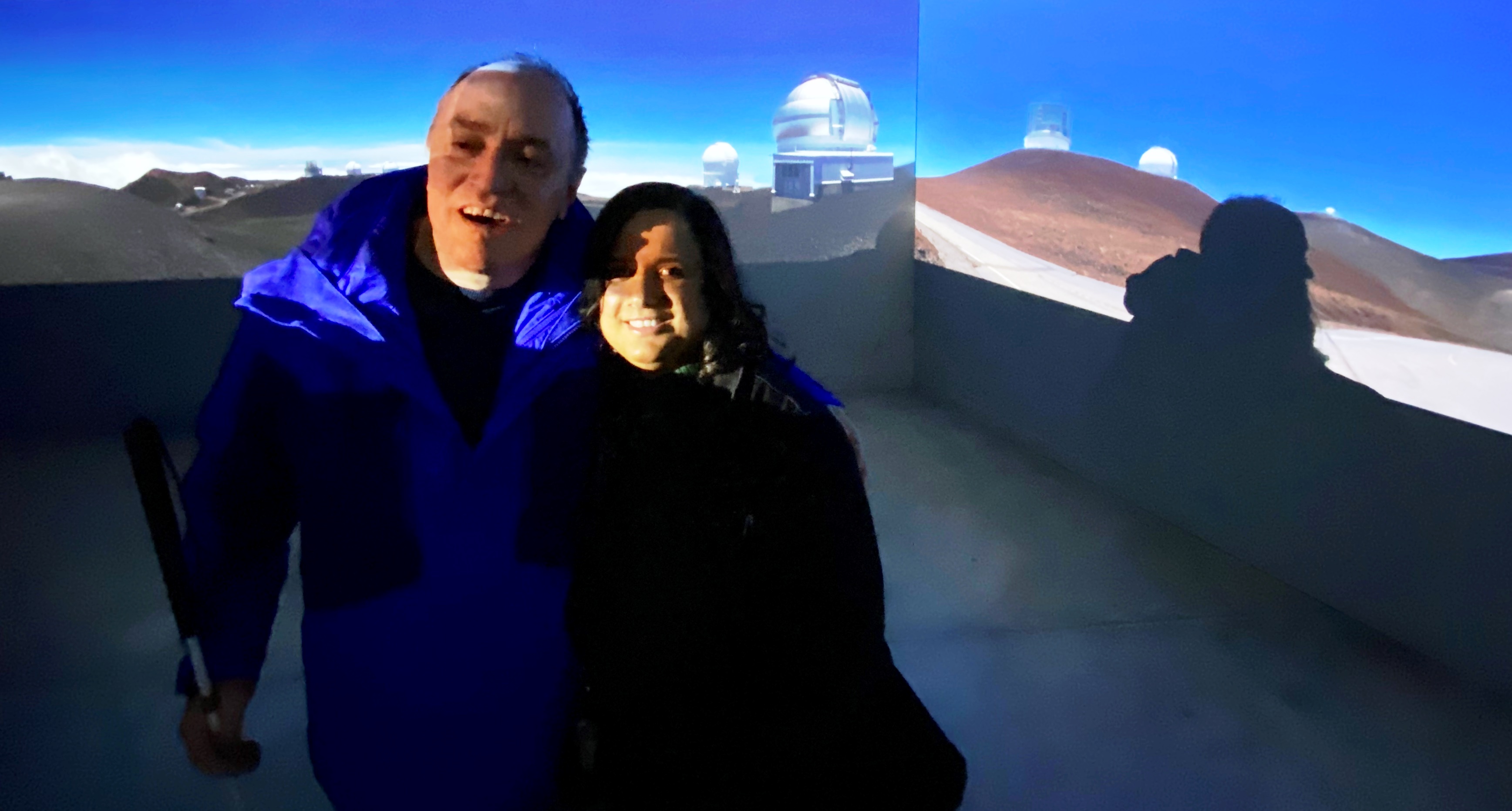 Kristy and Shawn with the projected image of a lush Hawaiian landscape behind them