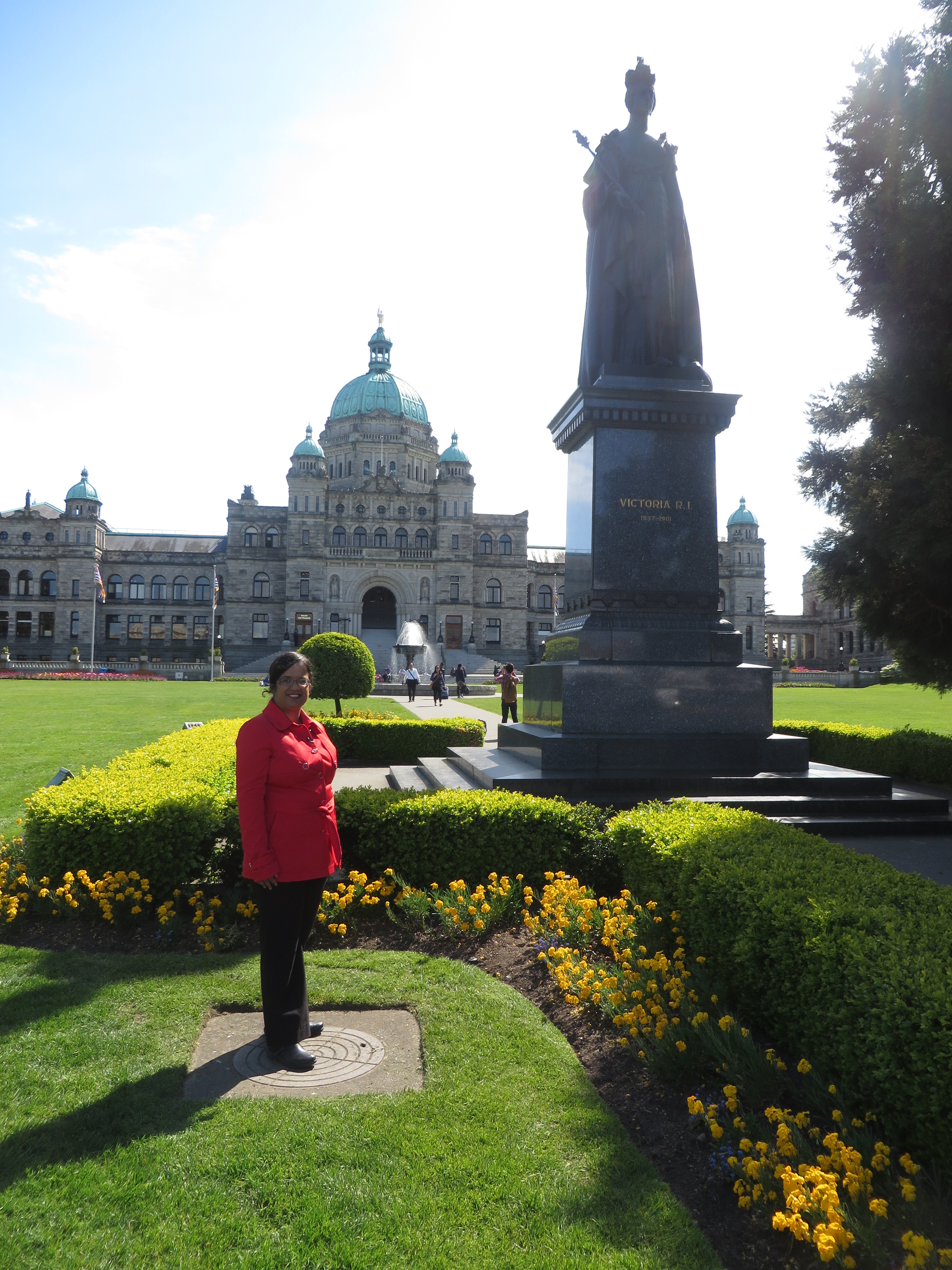 Kristy at the foot of Queen Victoria's stone statue with the BC Legislature in the background